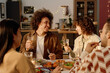 © AnnaStills - Biracial couple holding glasses with apple juice while sitting at festive table and looking at each other