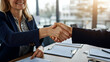 © Kevin - A professional scene featuring a mid-aged businesswoman smiling warmly while shaking hands during an office meeting. Perfect for corporate, HR, or business-related projects.