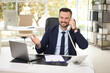 © New Africa - Happy banker talking on phone at table in office