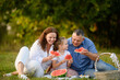 © GRON777 - Parents and girl enjoying picnic in sunny park, enjoying refreshing watermelon slices, chatting and laughing. Summer snack in park. Happy family having summer picnic on weekend outdoors