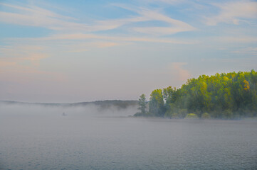 Wall Mural - autumn's soft landscape, with morning fog hovering over the river. a fisherman in his boat, surround