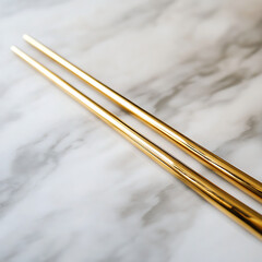 close-up of a pair of golden chopsticks on a smooth, marble surface with soft ambient light, perfect for an upscale branding design.