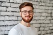 © NEW STUDIO - Portrait of smiling bearded man wearing glasses and white t-shirt against brick wall