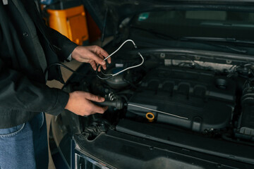 Fototapete - Mechanic using a diagnostic tool to check a car engine in a workshop, demonstrating vehicle maintenance and repair
