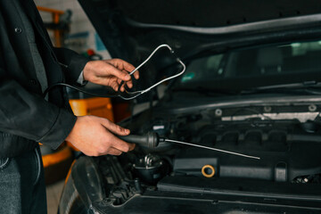Fototapete - Mechanic using a diagnostic tool to check a car engine in a workshop, demonstrating vehicle maintenance and repair