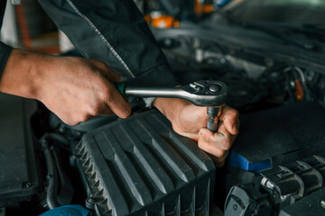 Aufkleber - Mechanic tightening a bolt on a car engine using a ratchet wrench in a professional workshop setting