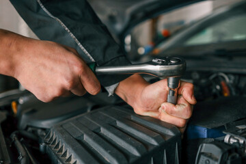 Aufkleber - Mechanic tightening a bolt on a car engine using a ratchet wrench in a professional workshop setting