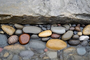 Leinwandbilder - Smooth beach pebbles covered by gentle waves on a calm shoreline during low tide. Generative AI