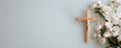 © W.O.W - Christian background with golden crucifix on neutral light blue wall background decorated with branches of white flowers.