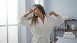 © Krakenimages.com - Beautiful young woman in a spa stretching in a luxurious wellness room, wearing a white robe, with brunette hair, in an indoor beauty center