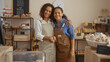 © Krakenimages.com - Latin women bakers smiling and standing together in a cozy bakery interior filled with a variety of bread and pastries, showcasing their warm partnership and happy workspace.