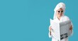 © Pixel-Shot - Pretty young woman in bathrobe reading newspaper on blue background with space for text
