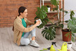 © Pixel-Shot - Young woman cleaning dust from leaves of Monstera houseplant at home