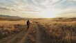© musa - Cyclist rides dirt road at sunset in rural landscape.
