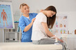 © Pixel-Shot - Mature female osteopath working with young woman on couch in clinic