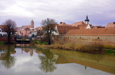 Wall Mural - Danube River flowing under a small bridge with church spires and medieval town walls in the background