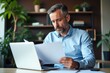 © SimpleDesignStudio - Focused Businessman Analyzing Documents at Modern Workspace with Plants and Laptop: A Portrait of Professionalism and Productivity