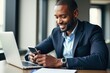 © SimpleDesignStudio - Professional African American Man Engaged in Mobile Communication and Working on Laptop in Modern Office Setting