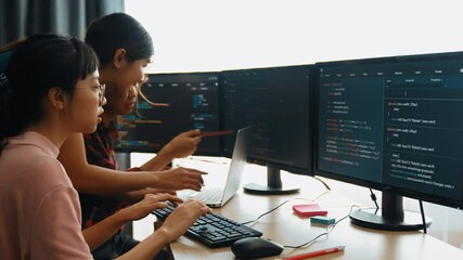 Slow motion back end software developer engineer for computer programming working together on debugging writing computing code, solving complex algorithms display on monitor in office. Burgeoning