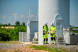 © Hip.hub - Workers examine plans near a wind turbine in a renewable energy field on a sunny day