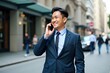 © SimpleDesignStudio - Confident Businessman in Suit Joyfully Talking on Smartphone While Walking Down City Street with Urban Background