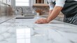 © NAIMAH - Craftsman inspecting a polished marble countertop in a modern kitchen.