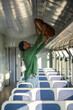 © DimaBerlin - Man traveler lifts backpack onto overhead luggage rack in train, settling in for long solo journey. Public transport, solo adventure, backpacking, transit convenience, seat arrangement, railway travel