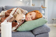 © Studio Romantic - Sick upset depressed young millennial red-haired girl lying on couch feeling bad, sad tired exhausted girl resting trying to sleep feeling cold, covered with warm blanket, suffering with virus