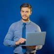 © MediaPro - Homme en Chemise Bleue Tenant un Ordinateur Portable sur un Fond Bleu Minimaliste