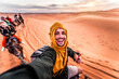 © Davide Angelini - Happy tourist having fun enjoying group camel ride tour in the desert - Travel, life style, vacation activities and adventure concept