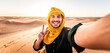 © Davide Angelini - Happy male tourist taking selfie on sand dunes in the Africa desert, Sahara National Park - Influencer travel blogger enjoying trip while takes self portrait - Summer vacation and weekend activities