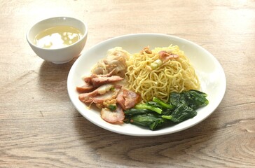 Wall Mural - dry Chinese egg yellow noodles with red barbecue pork and dumpling in on plate with clear soup cup