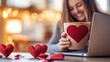 © Tobi - A professional setting with a woman holding heart latte art coffee, smiling warmly at a romantic message on her laptop