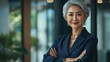 © Johannes - Happy smiling confident middle aged Asian older senior female leader businesswoman standing in modern office workplace looking at camera arms crossed. Business successful executive concept. Portrait.