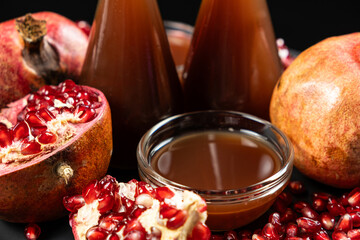 Pomegranate vinegar in a glass bowl among fresh pomegranate fruits.