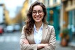 © Robbie Smith 1  - Young happy pretty smiling professional business woman, happy confident positive female entrepreneur standing outdoor on street arms crossed, looking at camera