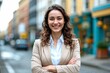 © Robbie Smith 1  - Young happy pretty smiling professional business woman, happy confident positive female entrepreneur standing outdoor on street arms crossed, looking at camera