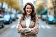 © Robbie Smith 1  - Young happy pretty smiling professional business woman, happy confident positive female entrepreneur standing outdoor on street arms crossed, looking at camera