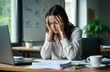 © miss irine - Businesswoman sits at desk looking stressed, overwhelmed. Holding head, appearing exhausted, in pain from hard work. Papers, documents on table indicating deadline problem at work. Appears