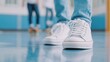 © Lion - A close up of a pair of sneakers and a skateboard on a school floor, with blurred friends skating in the background