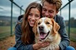 © miss irine - Young couple cuddles happy dog at animal shelter. Look happy, loving. Likely choosing pet for adoption. Outdoor scene. Daytime. Couple looks affectionate, kind towards dog. Possible volunteer new