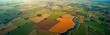 © miss irine - Aerial view of agricultural landscape. Fields of different colors, shapes organized in regular pattern. River flows through landscape. Rural farm buildings, trees visible. Farmland management, tech
