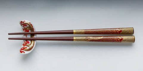 Elegant chopsticks with dragon design resting on a matching rest.