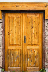 Rustic wooden door with metal handle on stone wall background