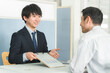 © buritora - 受付・窓口で男性客を接客する若いアジア人ビジネスマン