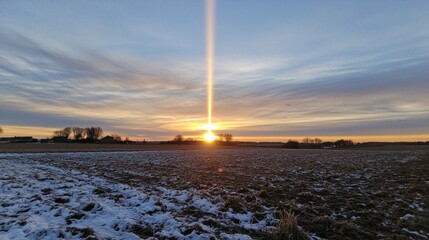 Winter sunset light beam over snowy field