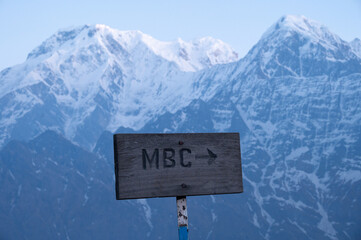 Wall Mural - A wood sign lead to Machapuchare base camp in Nepal with view of Mt.Annapurna South (7,219 m) and Mt.Hiunchuli (6,441 m) in the background.