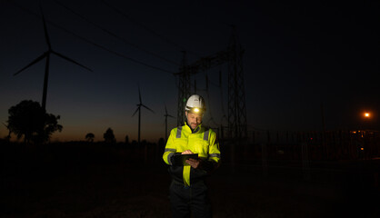 Fototapete - Engineer man working with tablet at windmill farm Generating electricity clean energy. Wind turbine farm generator by alternative green energy.