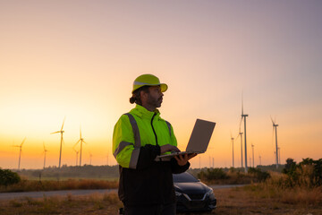 Aufkleber - Engineer working on laptop in front of wind turbines for checking wind turbines of the field during beautiful sunset. Alternative energy concept.
