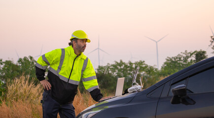 Aufkleber - Engineer working on laptop in front of wind turbines for checking wind turbines of the field during beautiful sunset. Alternative energy concept.